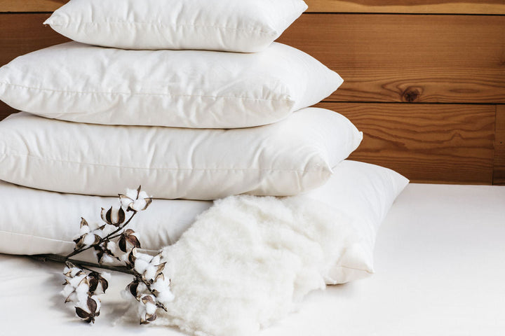 Holy Lamb Wool Filled Bed Pillows stacked on a surface with cotton decor.