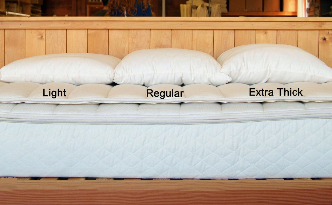 Light, Regular, and Extra Thick Holy Lamb Wool Filled Bed Pillows displayed on a bed mattress.