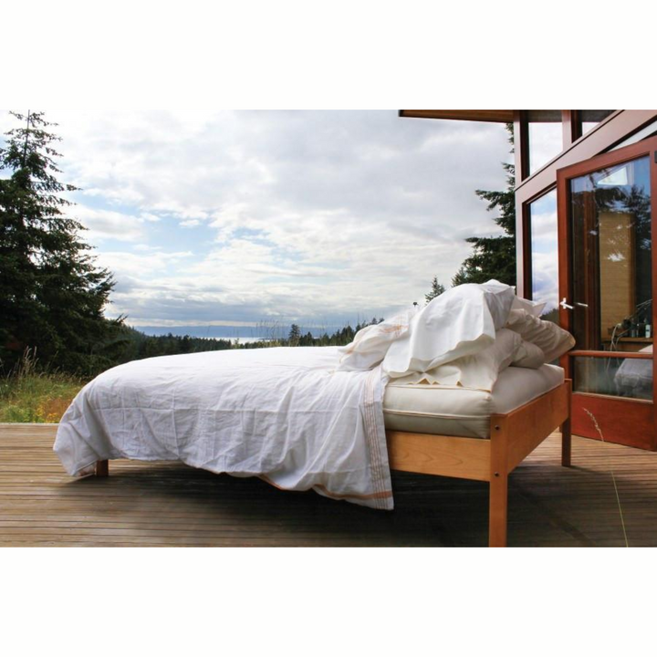 Soaring Heart Organic Cotton Wool Futon on a wooden bed with beautiful outdoor scenery.