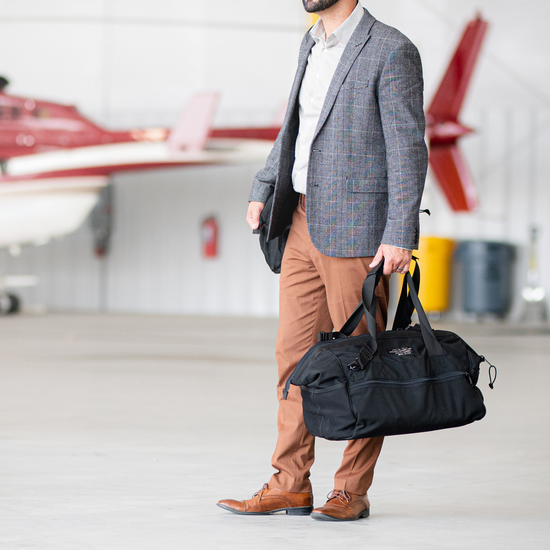 Man in blazer holding Faraday Cordura Utility Bag in a hangar setting.