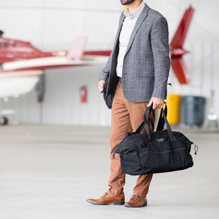 Man in blazer holding Faraday Cordura Utility Bag in a hangar setting.