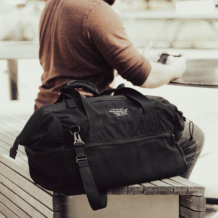 Faraday Cordura Utility Bag large black waterproof canvas on a table next to a person.
