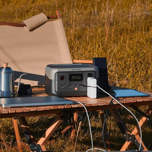 EcoFlow RIVER 2 portable power station on outdoor table, charging devices.