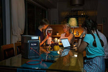 Load image into Gallery viewer, EcoFlow DELTA 1300 Portable Power Station in use, powering multiple devices on a dining table.
